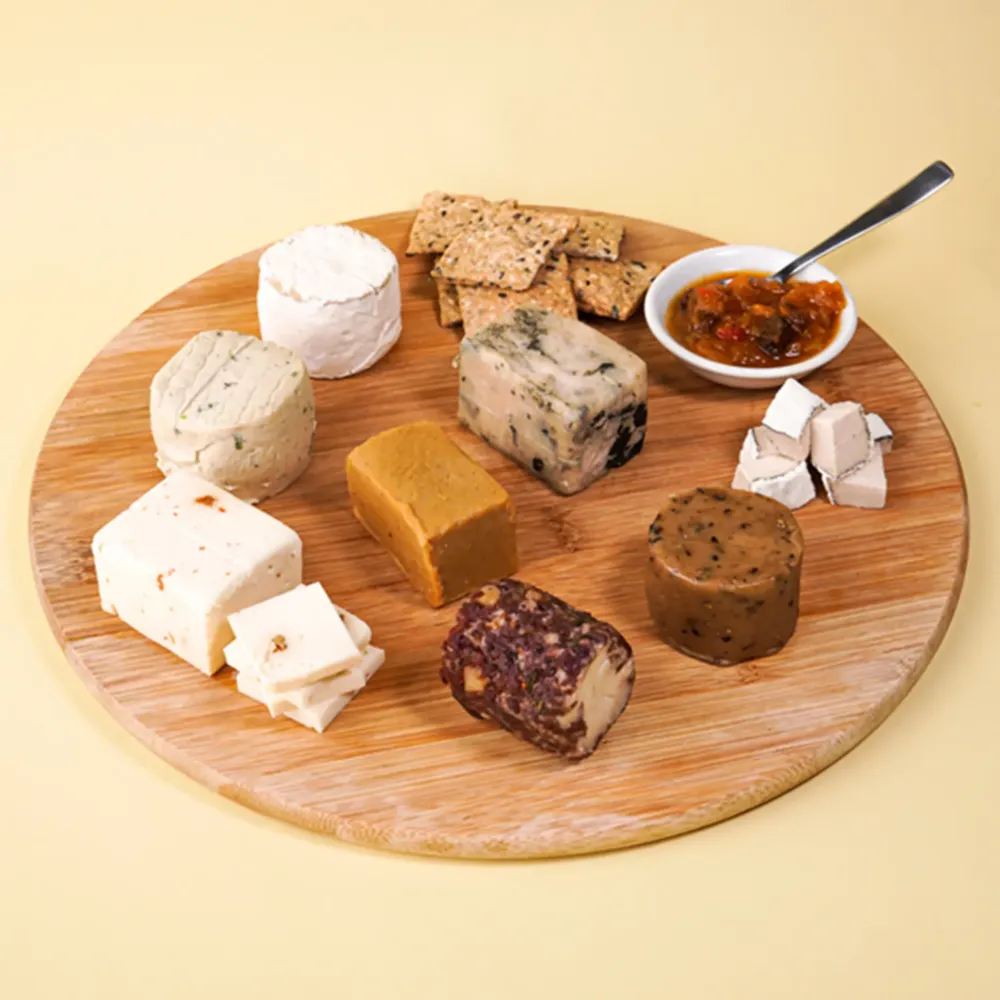 Taster Box cheeses on a round wooden board with crackers and chutney